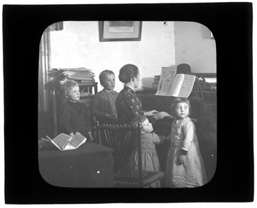 USA, Bay Ridge: Woman and children around a piano while she plays
