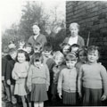 View: FDX0120 Frodsham: Miss Atkins School . She stands holding a garden rake. 
