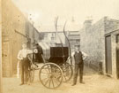 View: c13270 Carriage in a yard, with two men, possibly coachmen, standing to either side.