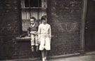 View: p1689 Young girl and small boy outside a terraced house.